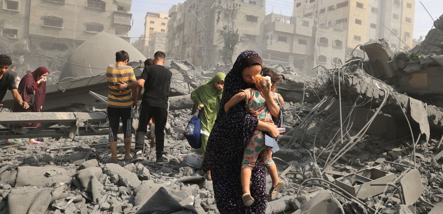 Madre protegiendo a su hija, entre las ruinas de un edificio derrumbado en la Franja de Gaza.