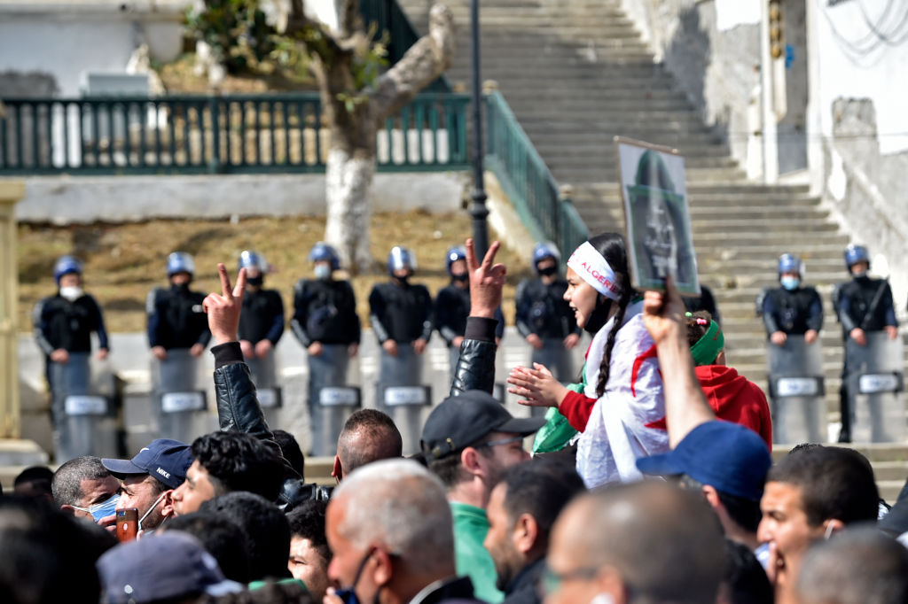 Fuerzas de seguridad argelinas vigilantes ante manifestantes durante las protestas contra el gobierno en la capital, Argel, el 5 de marzo de 2021. Miles de personas se manifestaron en Argel y otras ciudades de todo el país, confirmando la renovación del movimiento de protesta Hirak en las calles desde el segundo aniversario del levantamiento el 22 de febrero. (Fotografía RYAD KRAMDI / AFP) (Fotografía RYAD KRAMDI/AFP via Getty Images)