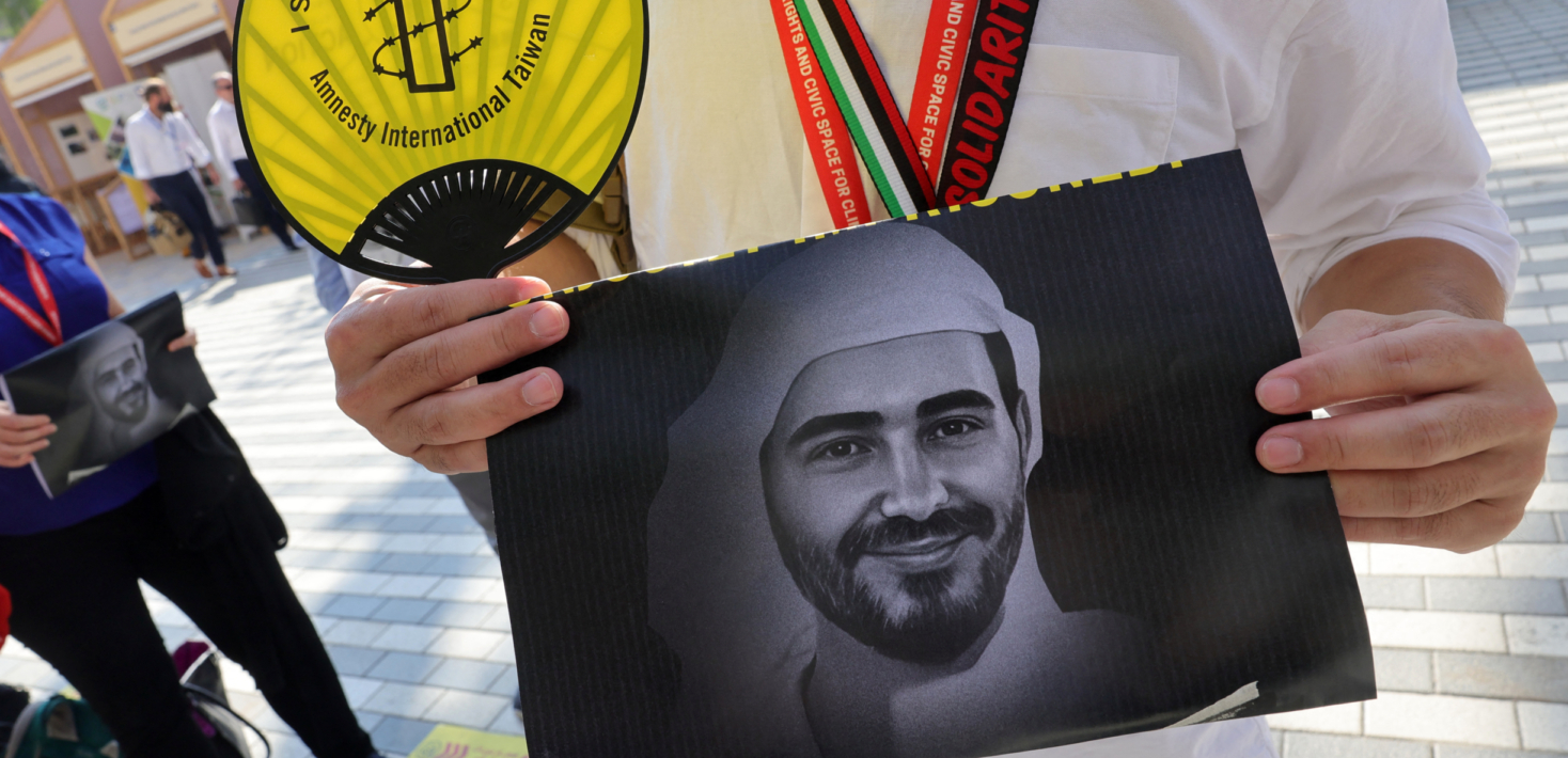 Activista de Amnistía Internacional sosteniendo un retrato del defensor emiratí de la democracia encarcelado Mohammed al Siddiq, durante una protesta para exigir la excarcelación de activistas, celebrada en Dubái el 9 de diciembre de 2023 ante la cumbre del clima de la ONU.