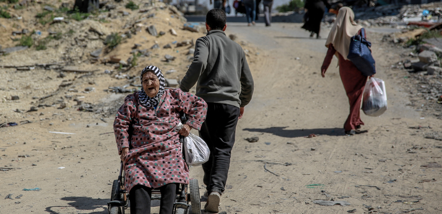 Un hombre tira de la silla de ruedas de una anciana palestina, mientras familias desplazadas transitan por la ciudad de Gaza, el 25 de marzo de 2024, durante el actual conflicto entre Israel y el movimiento palestino Hamás.