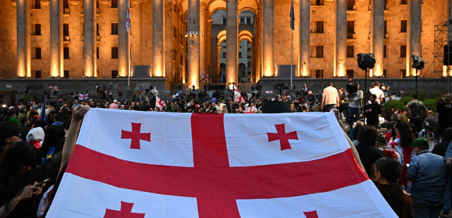 Manifestantes sostienen una bandera de Georgia durante una concentración a las puertas del parlamento georgiano en protesta por un controvertido proyecto ley sobre “influencia extranjera”, que, según advierte Bruselas, socava las aspiraciones de Georgia de formar parte de la Unión Europea.
