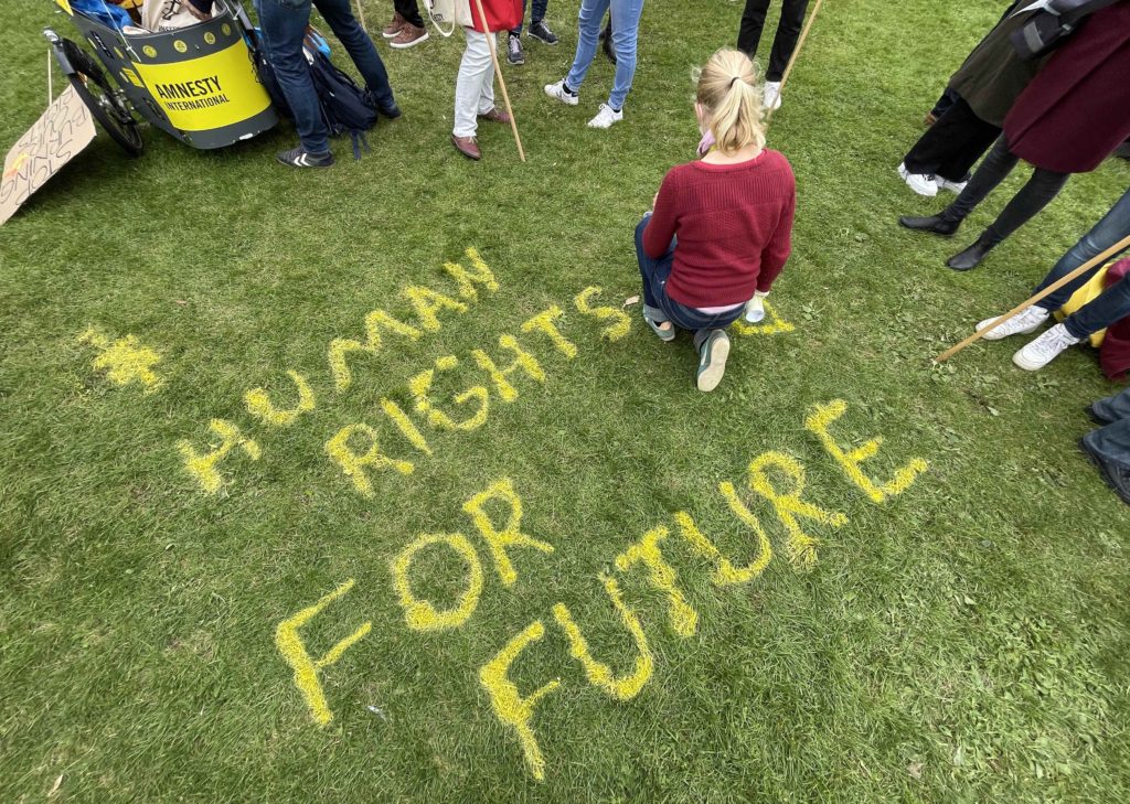Una activista pinta sobre la hierba las palabras “derechos humanos para el futuro”, Berlín, 2021