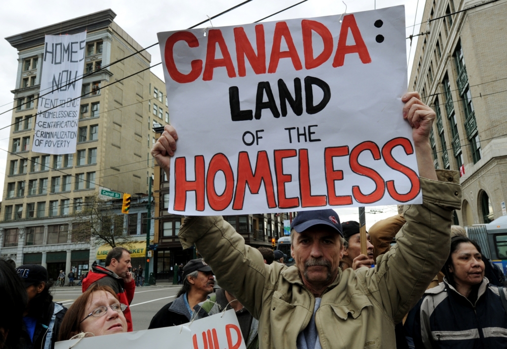A man holds up banner reading Canada Land of the homeless