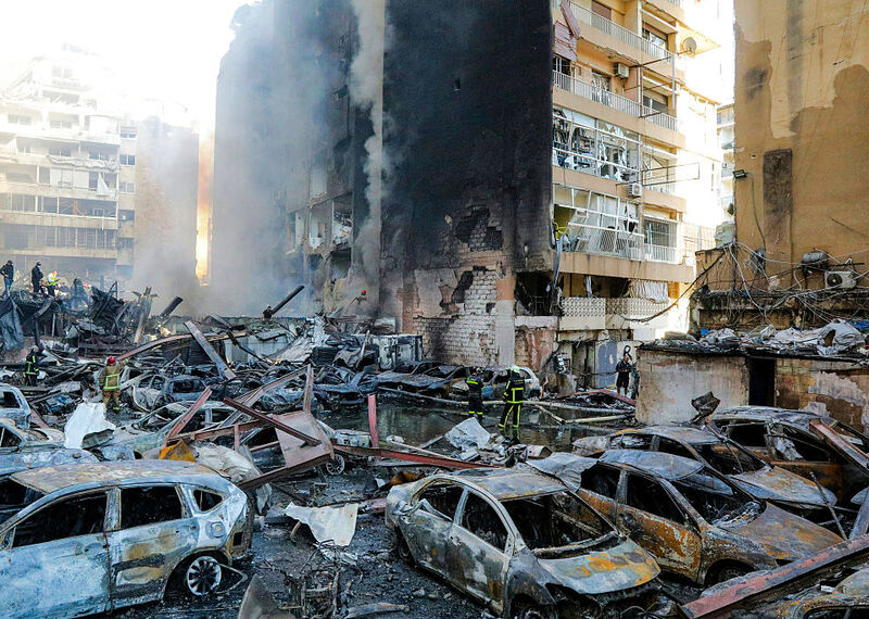 Coches aparecen destrozados mientras un bloque de pisos, cubierto de hollín negro, se desmorona.