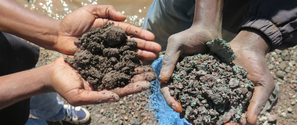 Dos mineros artesanales sostienen sendos montones de mineral de cobalto (izquierda) y de cobre (derecha) que han extraído del material de desecho de minas industriales activas e inactivas de las proximidades del lago Malo, en Kapata, a la afueras de Kolwezi, RDC.