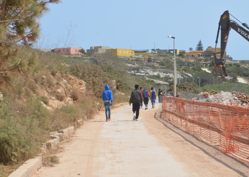 Un grupo de migrantes recorre un camino de tierra que va del centro de acogida a la localidad de Lampedusa. © Amnistía Internacional
