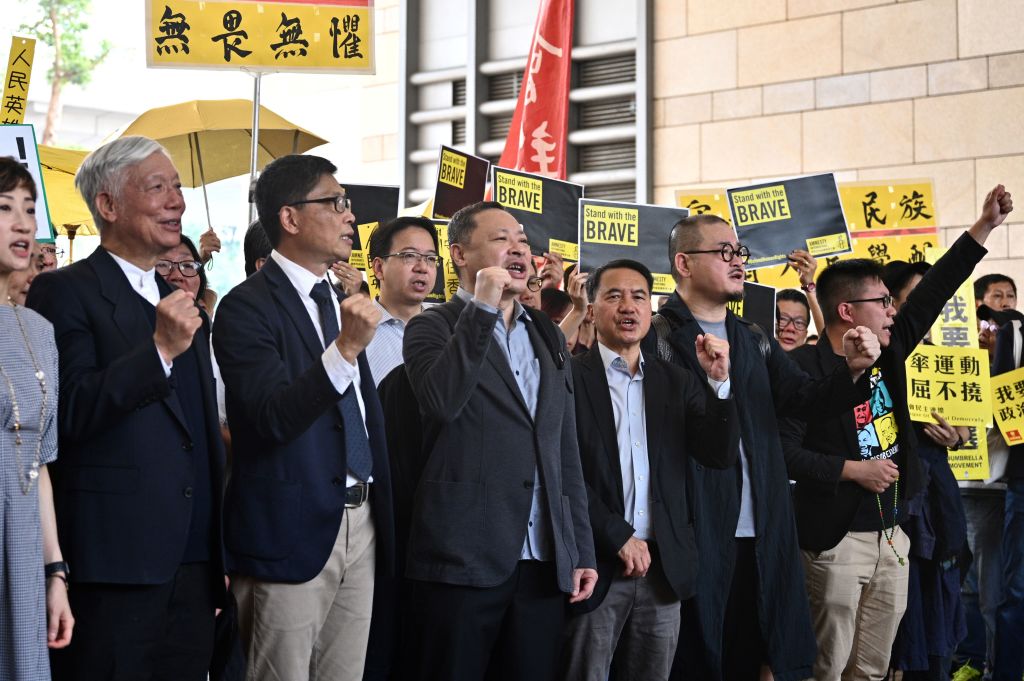 IMAGE ALT TEXT: (De izquierda a derecha): La legisladora pro democracia Tanya Chan, el ministro baptista Chu Yiu-ming, el profesor de Sociología Chan Kin-man, el profesor de Derecho Benny Tai, el ex legislador del Partido Democrático Lee Wing-tat, Shiu Ka-chun y el vicepresidente de la Liga de Socialdemócratas Raphael Wong corean consignas antes de entrar en la sala de vistas del Tribunal de Primera Instancia de Kowloon Occidental, en Hong Kong, el 9 de abril de 2019, para saber si van a ser encarcelados por su participación en las protestas de la “Revolución de los Paraguas” de 2014. Son algunas de las personas acusadas de cargos relacionados con escándalo en la vía pública, delito de la era colonial rara vez empleado en la actualidad, por su participación en las protestas de 2014 en las que reclamaban elecciones libres para liderar la ciudad.