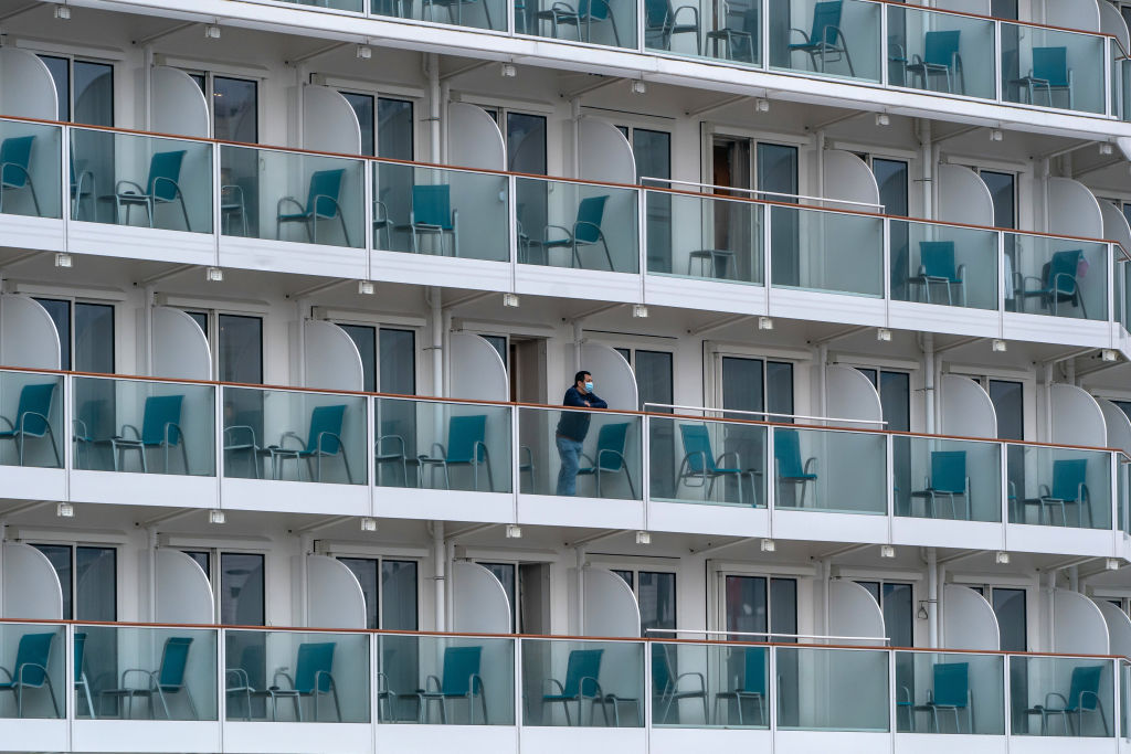 Un pasajero se asoma a un balcón a bordo del crucero The World Dream mientras permanece atracado en la terminal de cruceros de Kai Tak el 5 de febrero de 2020 en Hong Kong, China. (Foto: Anthony Kwan/Getty Images)