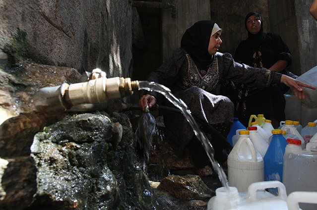 Mujeres palestinas llenan botellas de agua en el pueblo cisjordano de Qarawah Bani Zeid. © ABBAS MOMANI/AFP/Getty Images