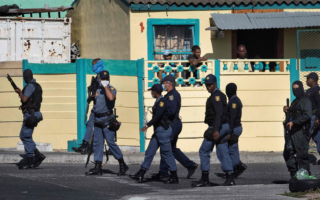 Miembros de la policía sudafricana patrullan la calle durante enfrentamientos con residentes en Sudáfrica.