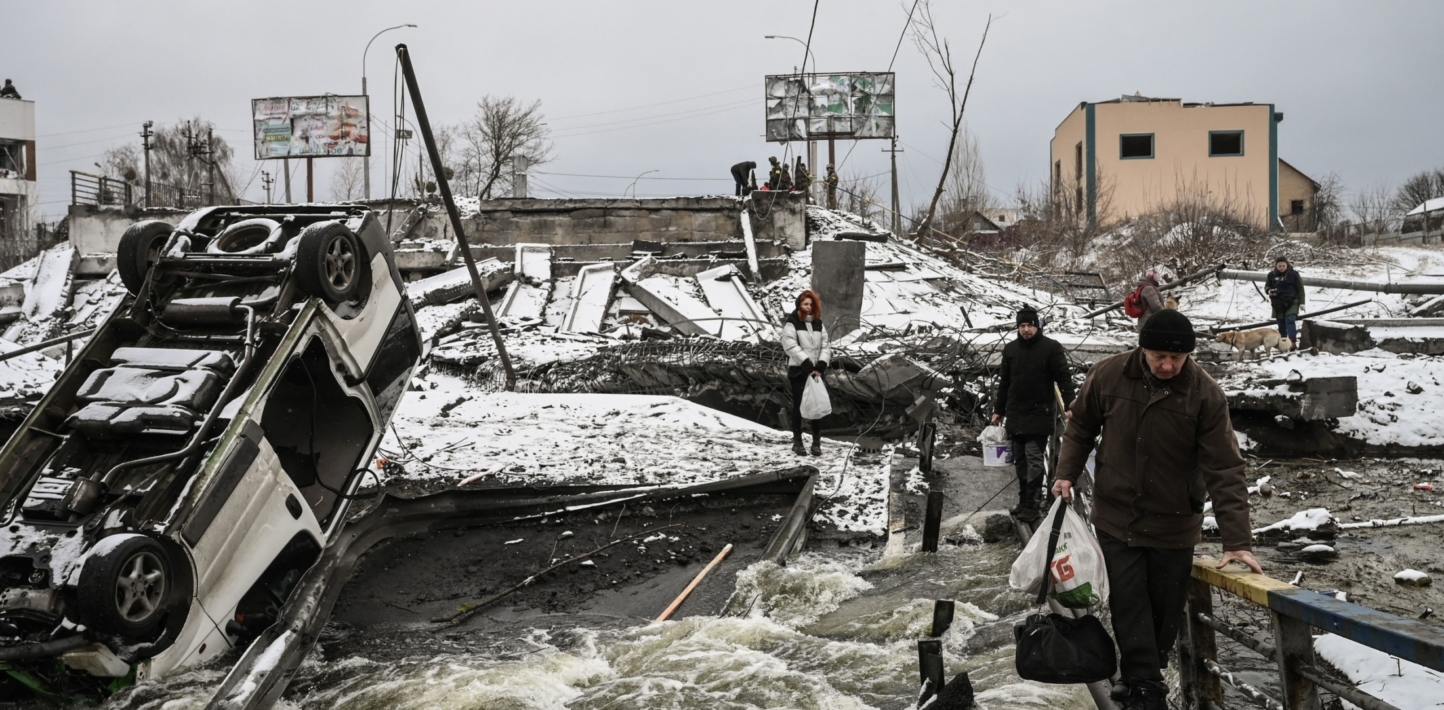 Civilians cross a river on a blown up bridge on Kyivs northern front on March 1, 2022.