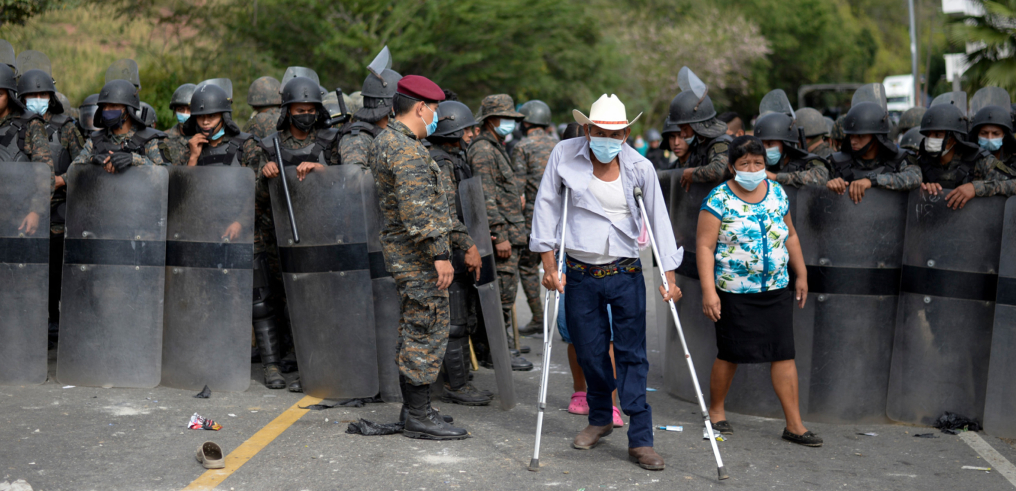Guatemalan Army soldiers open the way to a man on crutches after clashes with Honduran migrants, part of a caravan heading to the United States, erupted in Vado Hondo, Guatemala on January 17, 2021