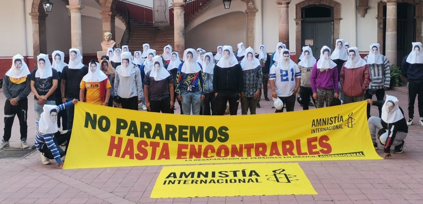 Demonstrators pose in masks with the faces of Mexico's 43 missing student teachers