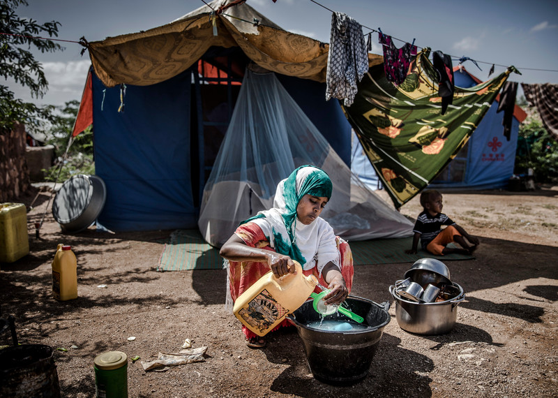 Une jeune femme et son enfant déplacés en raison de fortes pluies dans la région de Beledweyne, en Somalie, sont assis devant leur tente et font la vaisselle. Le changement climatique a entraîné des cycles d’inondations et de sécheresses qui ont mis des centaines de milliers de personnes en danger et ont entraîné leur déplacement en Somalie.