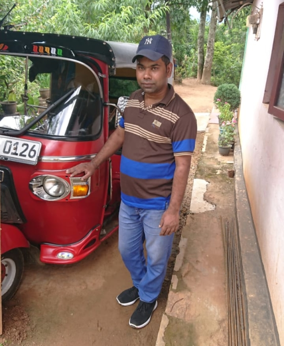Mohamed stands in front of his tuk-tuk