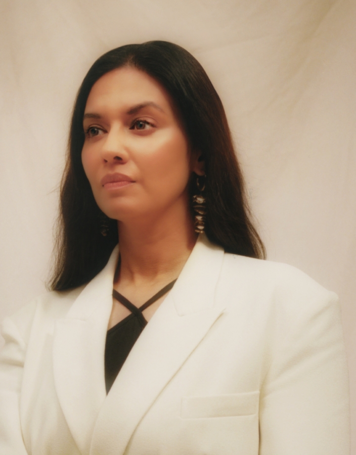 Elegantly dressed woman in a white suit with long dark hair.