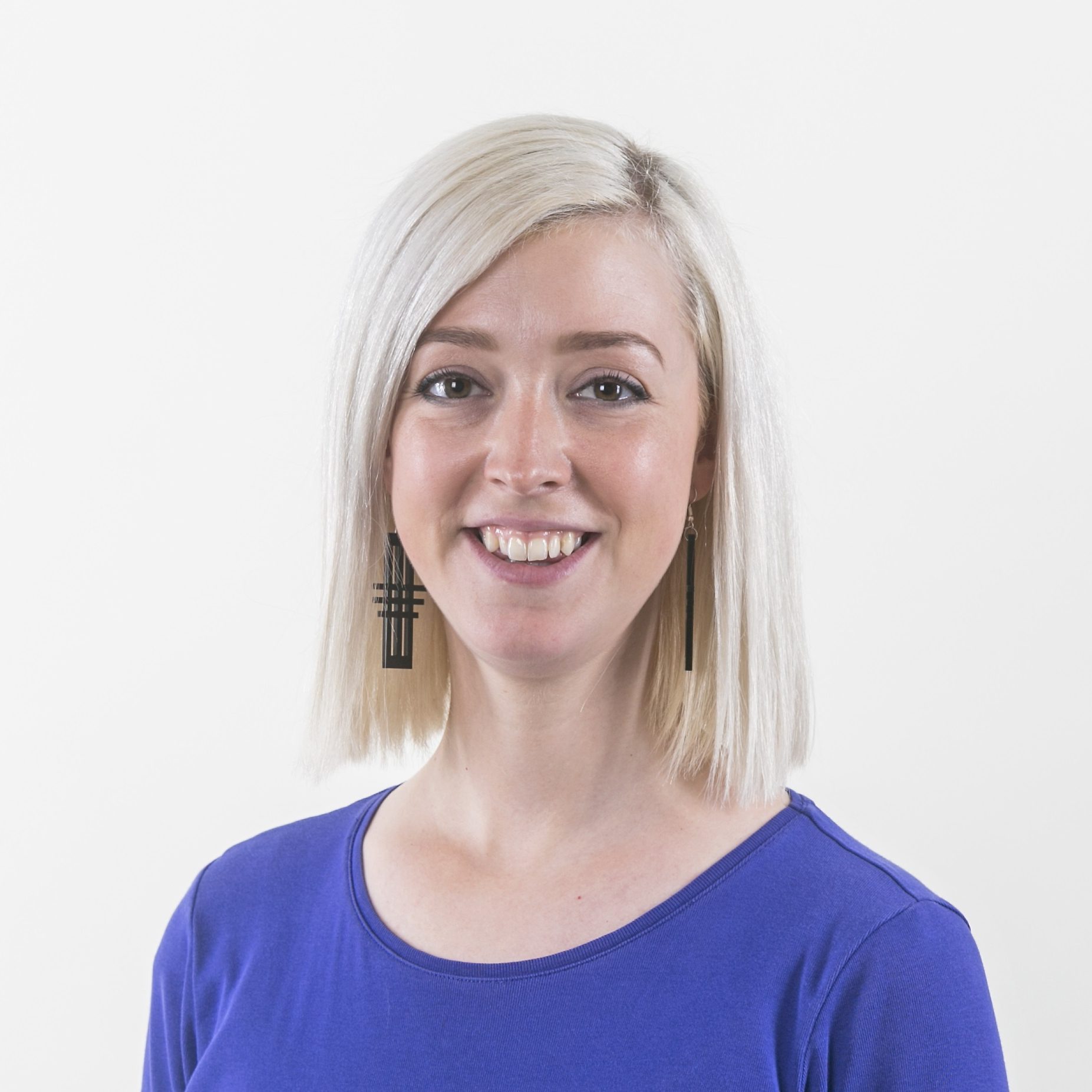 Jessica, smiling to camera, wearing a bright blue top against a plain white background.