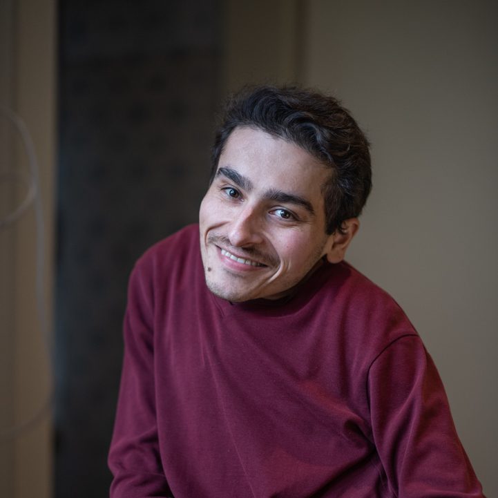 Mher smiling and wearing a burgundy jumper.
