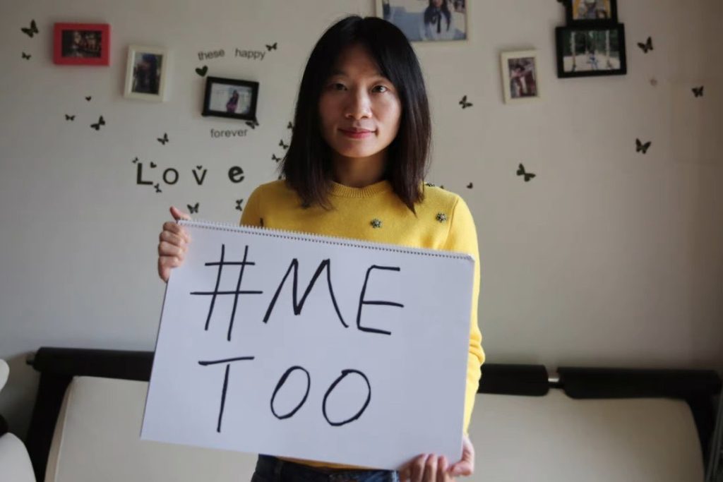 Huang Xueqin holds a sign that reads #MeToo.
