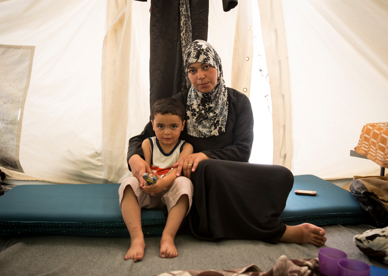 Hadi a trois ans et demi. Sa mère, Salwa Al Aji, est une enseignante de 38 ans qui vivait à Damas. Ils vivent dans le camp de Softex, situé près de la ville de Salonique, en Grèce. Salwa Al Aji a voyagé avec trois de ses enfants et son mari, qui ne peut pas marcher à cause d’une hernie discale. Elle a essayé de mettre en place une école dans le camp, mais il n’y a pas de livres et elle a peur des affrontements qui ont lieu tous les jours. Elle nous a dit : « Je ne voulais pas partir de Syrie, mais notre maison a été détruite ... J’ai fui la guerre pour trouver la guerre ici ».