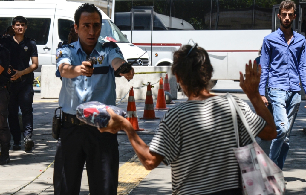 Un policier pointe son arme sur une femme qui apporte un paquet au palais de justice d'Ankara, le 18 juillet 2016.