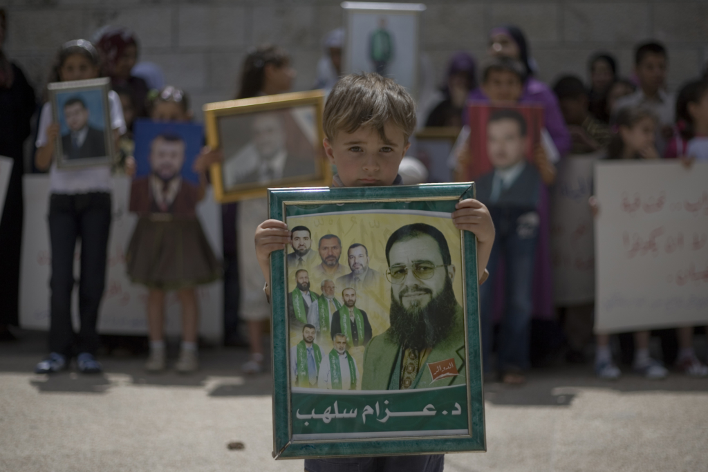 Un garçon palestinien tient la photo encadrée d'un de ses proches, un membre du Conseil législatif palestinien incarcéré, lors d'une manifestation organisée le 5 juillet 2009 à Ramallah, en Cisjordanie, pour demander la libération des prisonniers palestiniens détenus dans les prisons israéliennes © Fadi Arouri