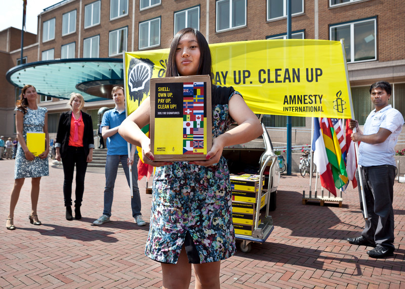 Des militants d'Amnesty devant les bureaux de Shell avec une pétition de plus de 300 000 signatures demandant à la compagnie pétrolière d'indemniser les habitants du delta du Niger et de nettoyer la zone contaminée. La Haye, Pays-Bas, 4 juillet 2012. © Jorn van Eck/Amnesty International
