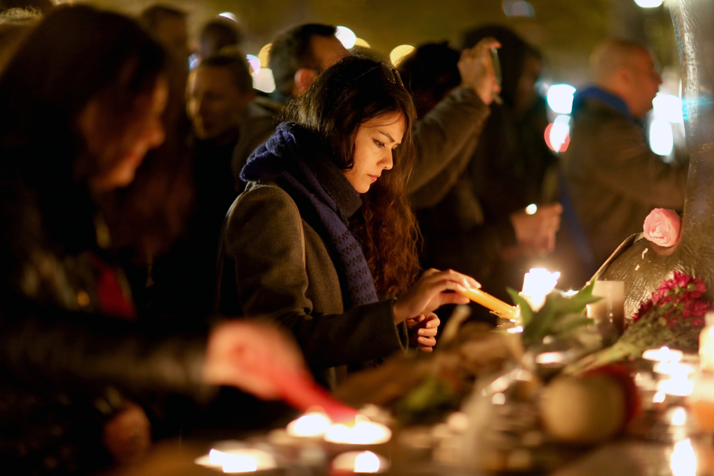 Une femme allume une bougie lors d'un rassemblement spontané en hommage aux victimes des attenats du 13 novembre à Paris. 14 novembre 2015. © Pierre Suu/Getty Images