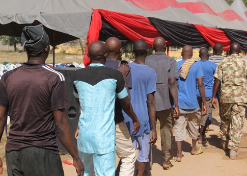 Lors d'une cérémonie militaire dans le camp de l'armée de Giwa, des hommes détenus depuis quatre ans maximum sans avoir été inculpés, pour des liens supposés avec Boko Haram, marchent en ligne après avoir été libérés et livrés aux agents gouvernementaux pour être  