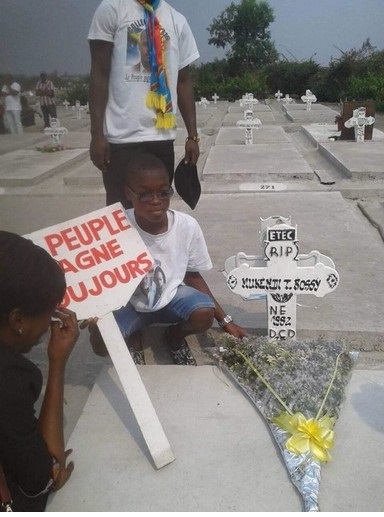 Kelly Tshimanga dépose des fleurs sur la tombe de son père. Son père, Rossy Mukendi Tshimanga a été tué d'une balle au ventre à l'église catholique de Saint Benoît le 25 février 2018.