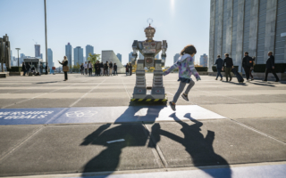 Image shows a robot in a public space with a child running past it