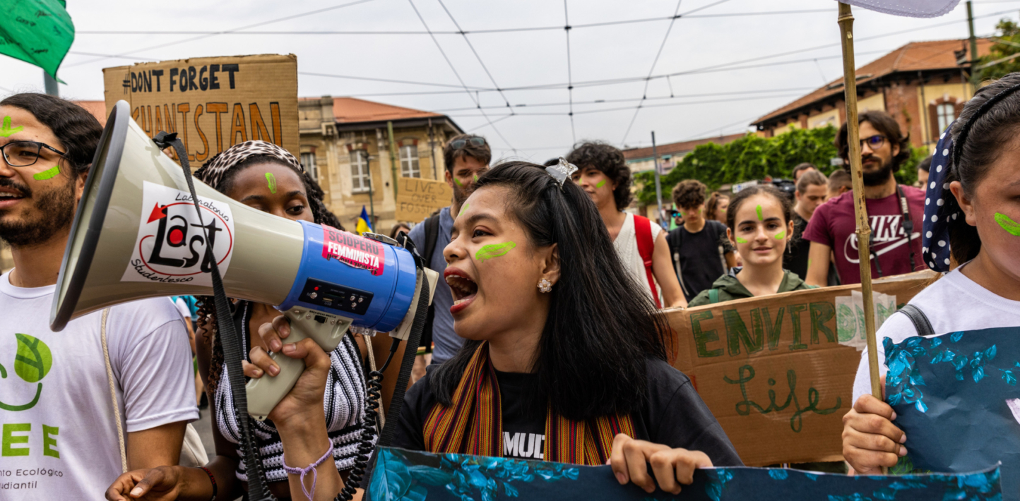 Protestors in hold Turin hold up banners and speak down a megaphone