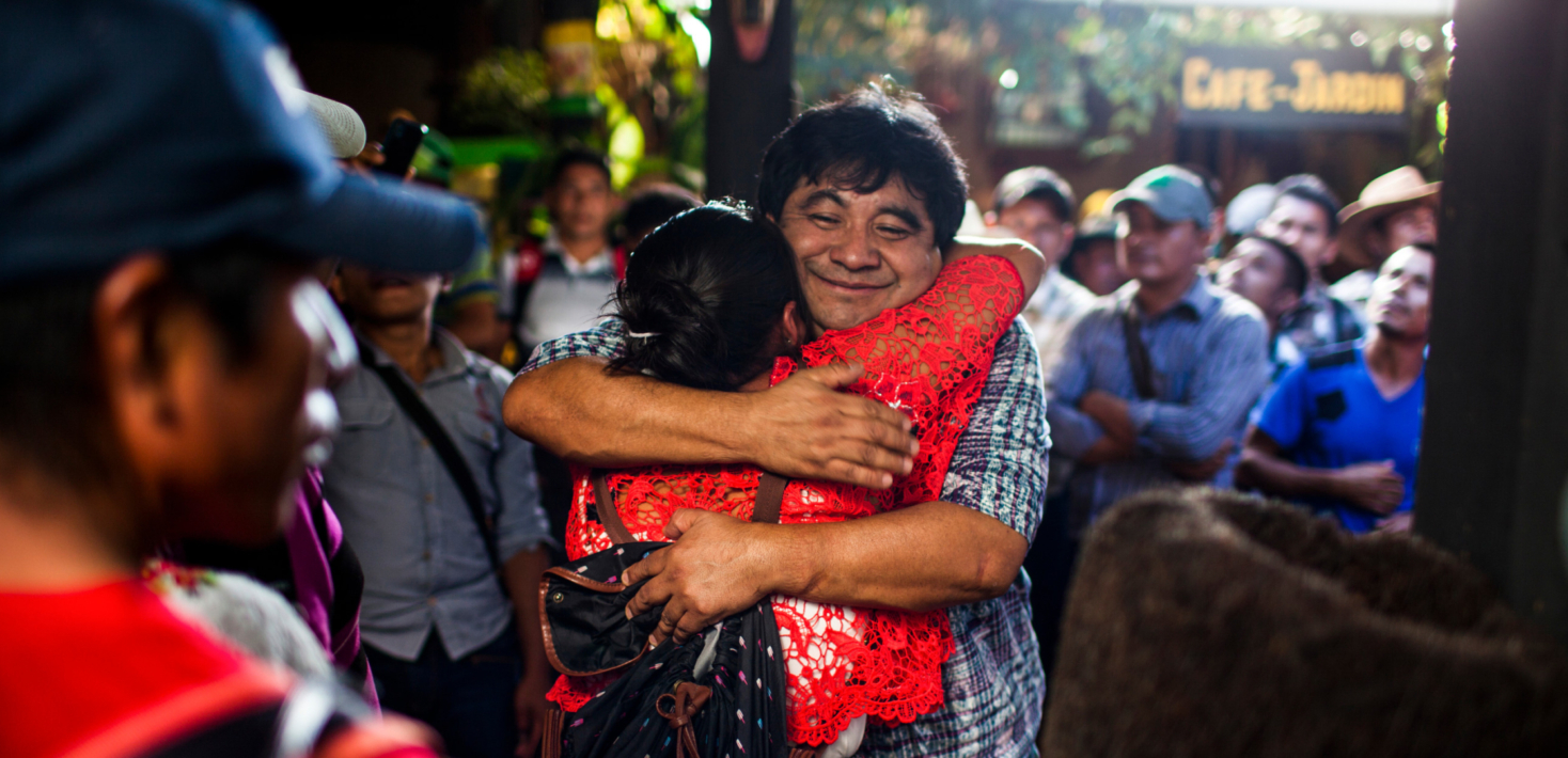 Two people hugging with a big emotional smile and a crowd standing around them.