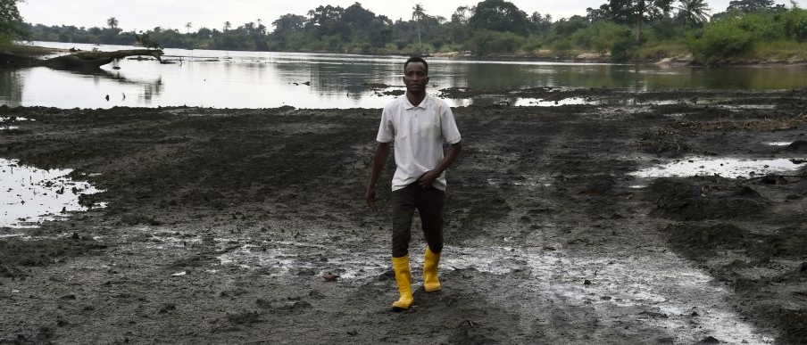 A farmer walks on a marshy shore of a river polluted by oil spills in Ogoniland in Rivers State