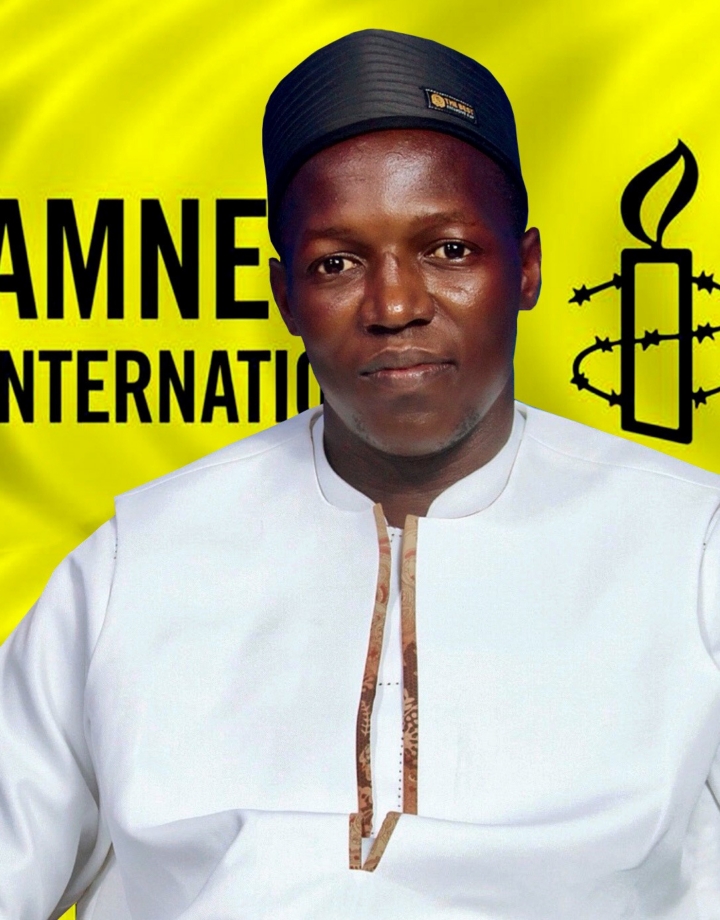 Papa looking at the camara with a black hat and white shirt, Amnesty yellow logo at the back.