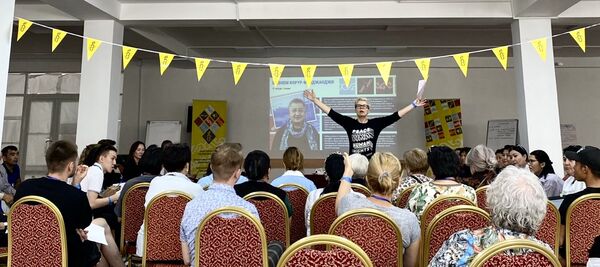 Стася Денисова воздевает руки перед аудиторией школьных учителей