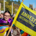 A person holds an Amnesty flag and celebrates Pride in Hungary.