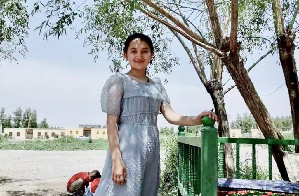kamile standing next to a green fence
